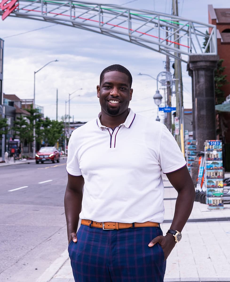 Michael Tay debout à côté de l’enseigne de la Petite Italie